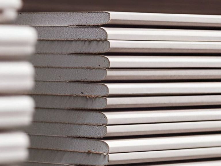 Ein Stapel Gipsplatten von der Kante her fotografiert, helle Kartonlagen wechseln sich mit dem grauen Kern ab.